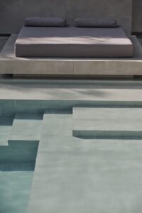 natural shades of layered tiled steps going into a swimming pool with built seating alongside