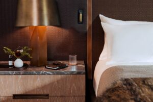 bed and bedside table detail with wood, leather and brass finishes