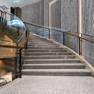 sweeping curved staircase with glass sides and textured film on the walls