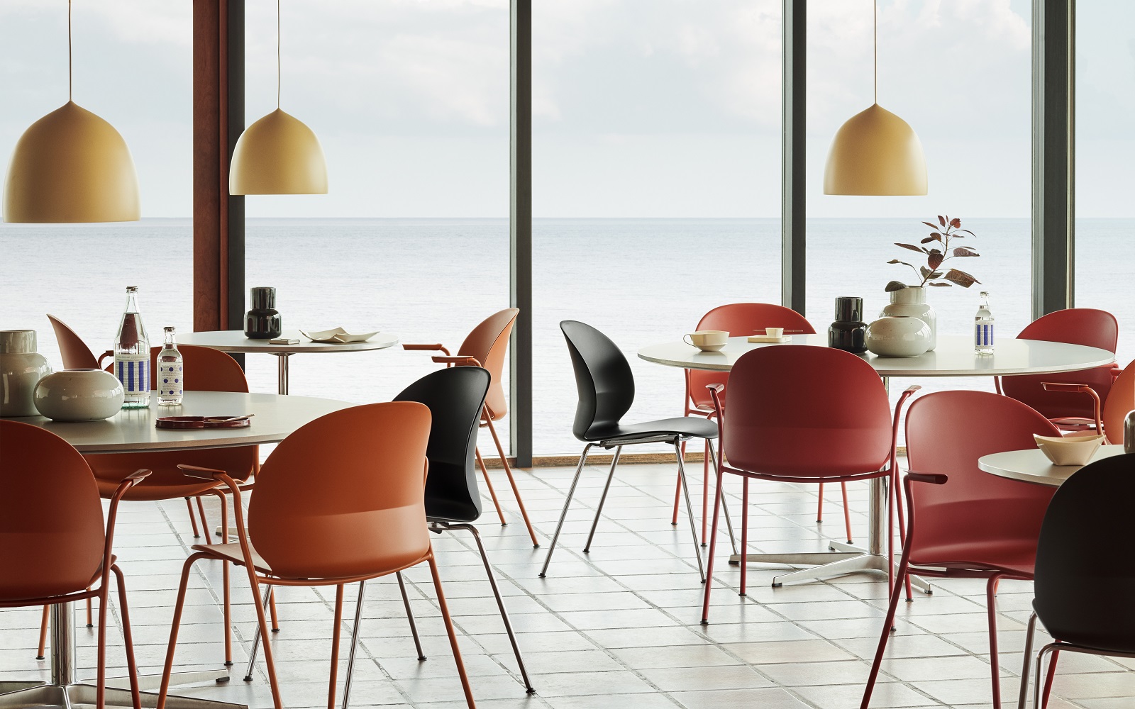 dark orange, red and black recycled chairs from ?Fritz Hansen in a restaurant setting with sea view