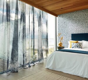 bedroom with floor to ceiling glass windows dressed in a lightly patterned sheer curtain