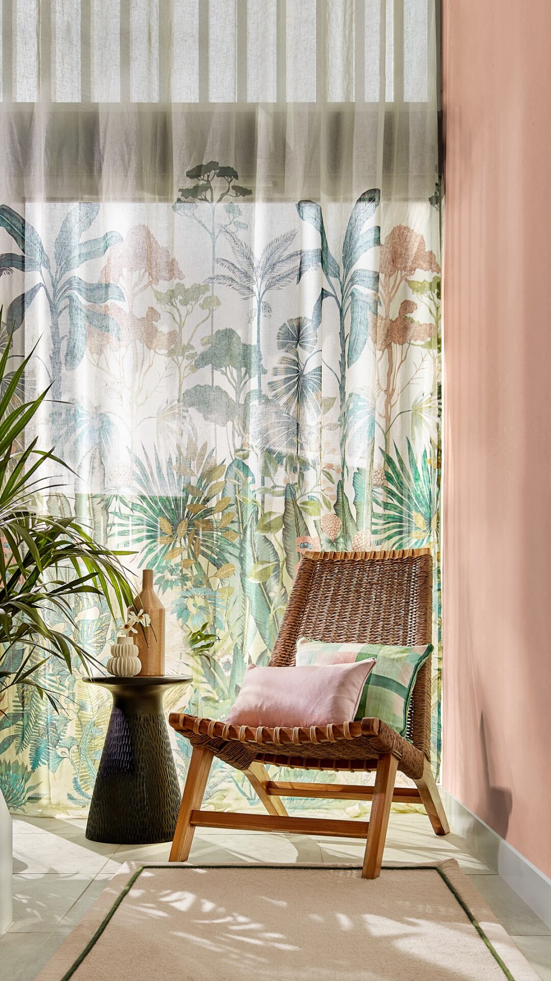 wooden chair and plants in a hallway in front of a window with sheer curtains with tropical plant pattern