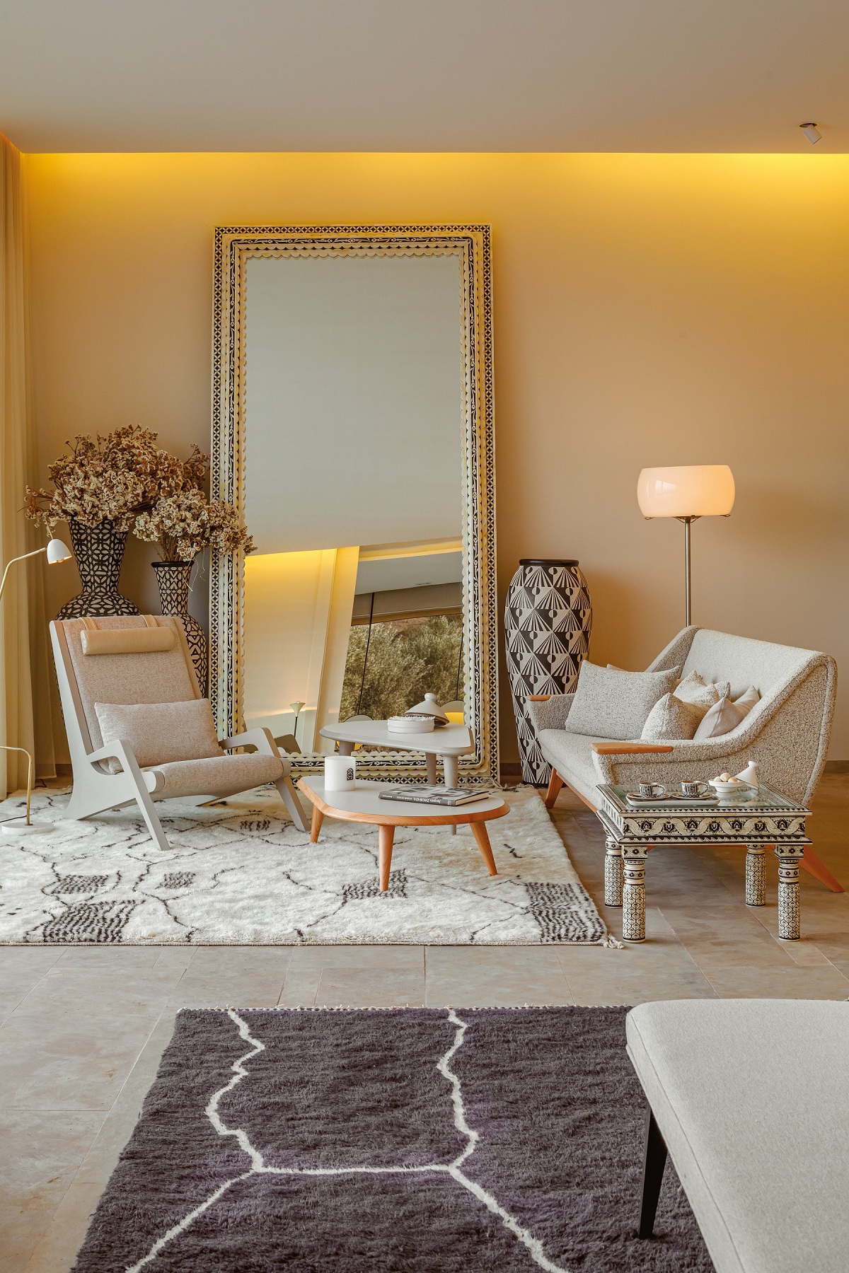guestroom with brown moroccan carpet on the floor with a cream and wood textured seating area in front of a mirror