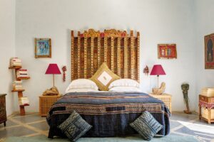 a traditional Moroccan wooden bed with bedisde lamps embedded in rock and a contemporary abstract bookshelf