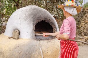 traditional moroccan clay oven with woman in straw hat baking bread