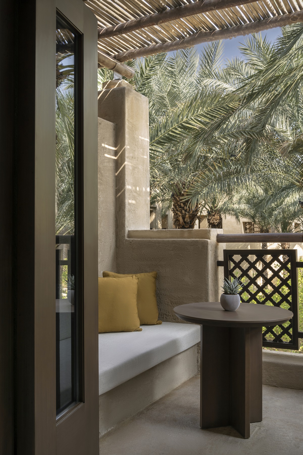 balcony corner at Bab Al Shams with built in seating looking across to palm trees