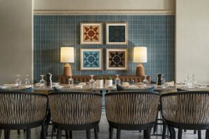 blue tiled wall with mosaic inspired artwork behind dining table