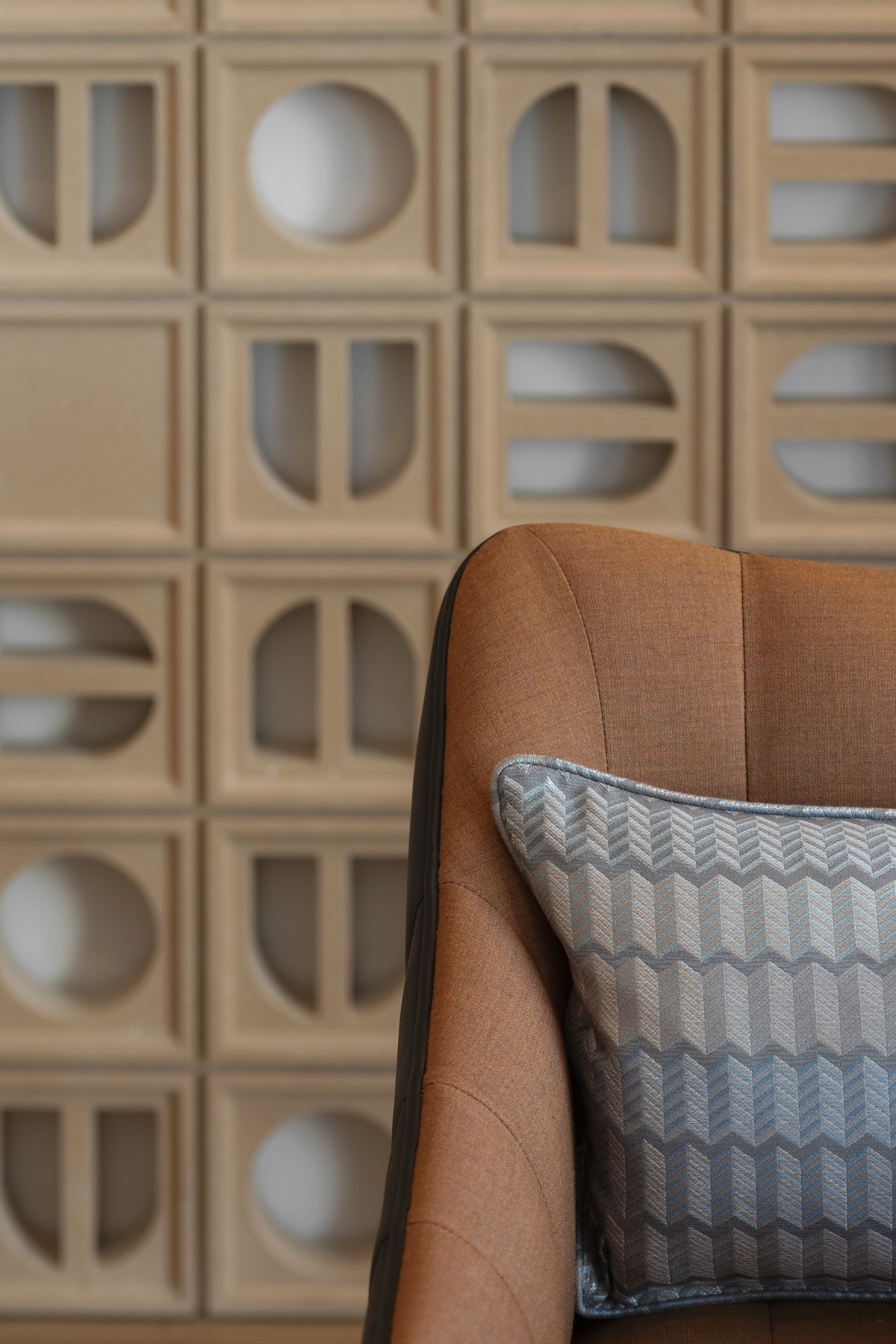 detail of corner of chair and blue patterned cushion if front of terracotta breezeblocks