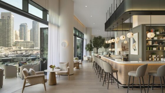 cream and beige seating around a bar with floor to ceiling windows looking out over dubai marina and city