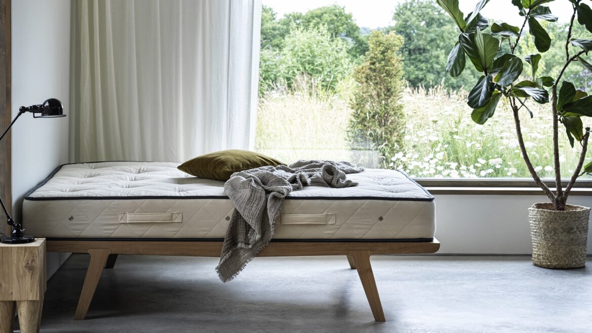 An unmade bed in front of window and countryside
