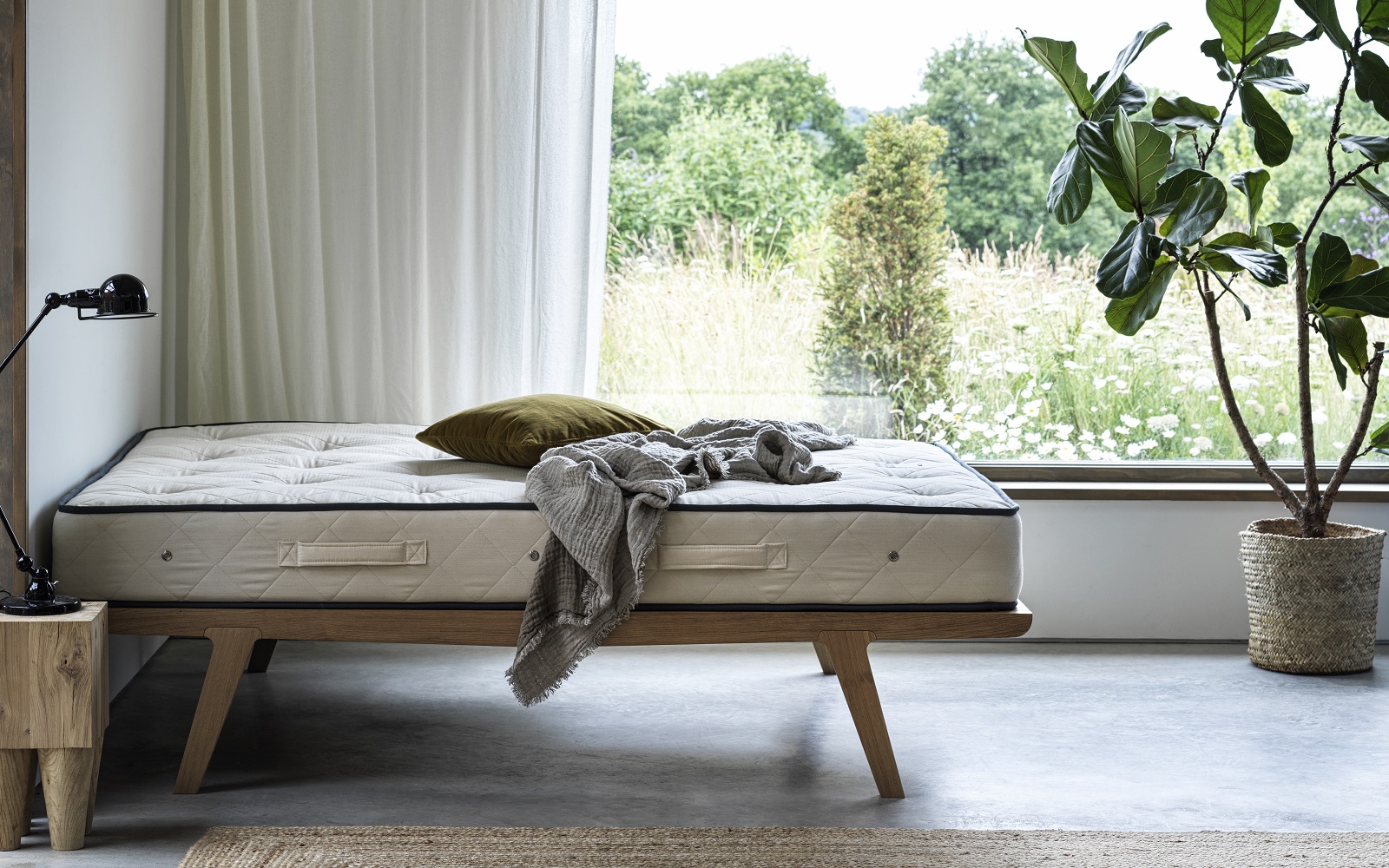 An unmade bed in front of window and countryside