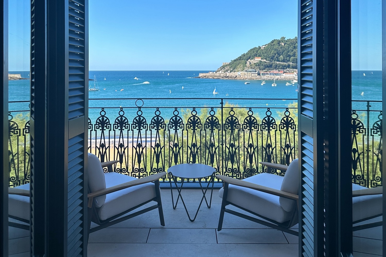 two chairs and a table on a balcony of Nobu San Sebastian in front of ornate balustrade with sea view