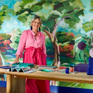 Interior designer sophie robinson in her studio with colourful painted backdrop and colour charts on the table