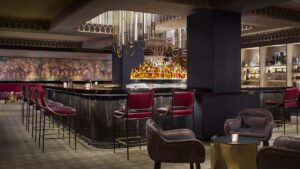 hotel bar with central bar under fluted chandelier and back wall painted with a music themed mural