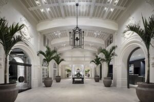 white cloister lobby with arches and palm trees in Boca Raton lobby by Rockwell Group
