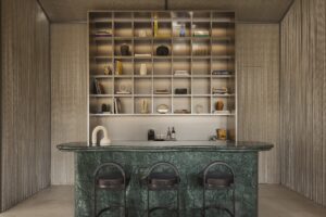 dark green marble bar in front of niche shelving with dispaly and sculptural elements on the bar in the Mondrian Shophouse Suite bar