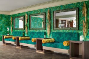 niche seating along a wall in green wallpaper and decorative mirrors with green mosaic details