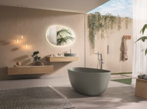 moss green freestanding bath in a bathroom with wall hung cabinets and a round mirror reflecting the plants outside