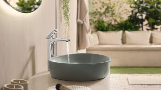 moss green rounded washbasin by villeroy & boch with water from tap and greenery in the background