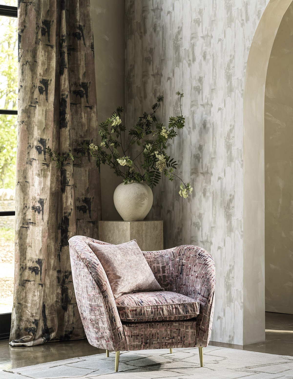 corner of a room with chair in front of a vase of flowers and patterned wallpaper and printed curtain fabric
