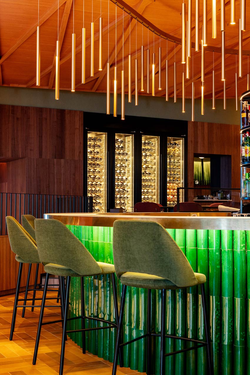 green clad bar with bar stools and overhead lighting in suspended rods