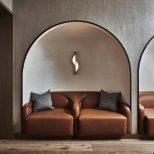 brown leather couch with curved detail handrest in arched niche