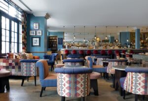 blue walls, wooden floors and patterned fabric on upholstered chairs in restaurant and bar setting 