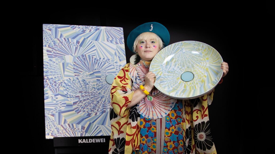 designer Bethan Laura Wood in colourful kimono and beret holding colourful basin from her collection for Kaldewei