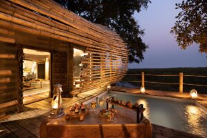 wooden poles on exterior of the safari guest suite with doors leading onto wooden deck and private swimming pool