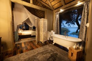 safari style guestroom made from recycled wood with traditional victorian bath looking out across the water
