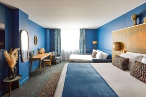 hotel guestroom with dark blue walls and a white ceiling with blue accents in soft furnishings