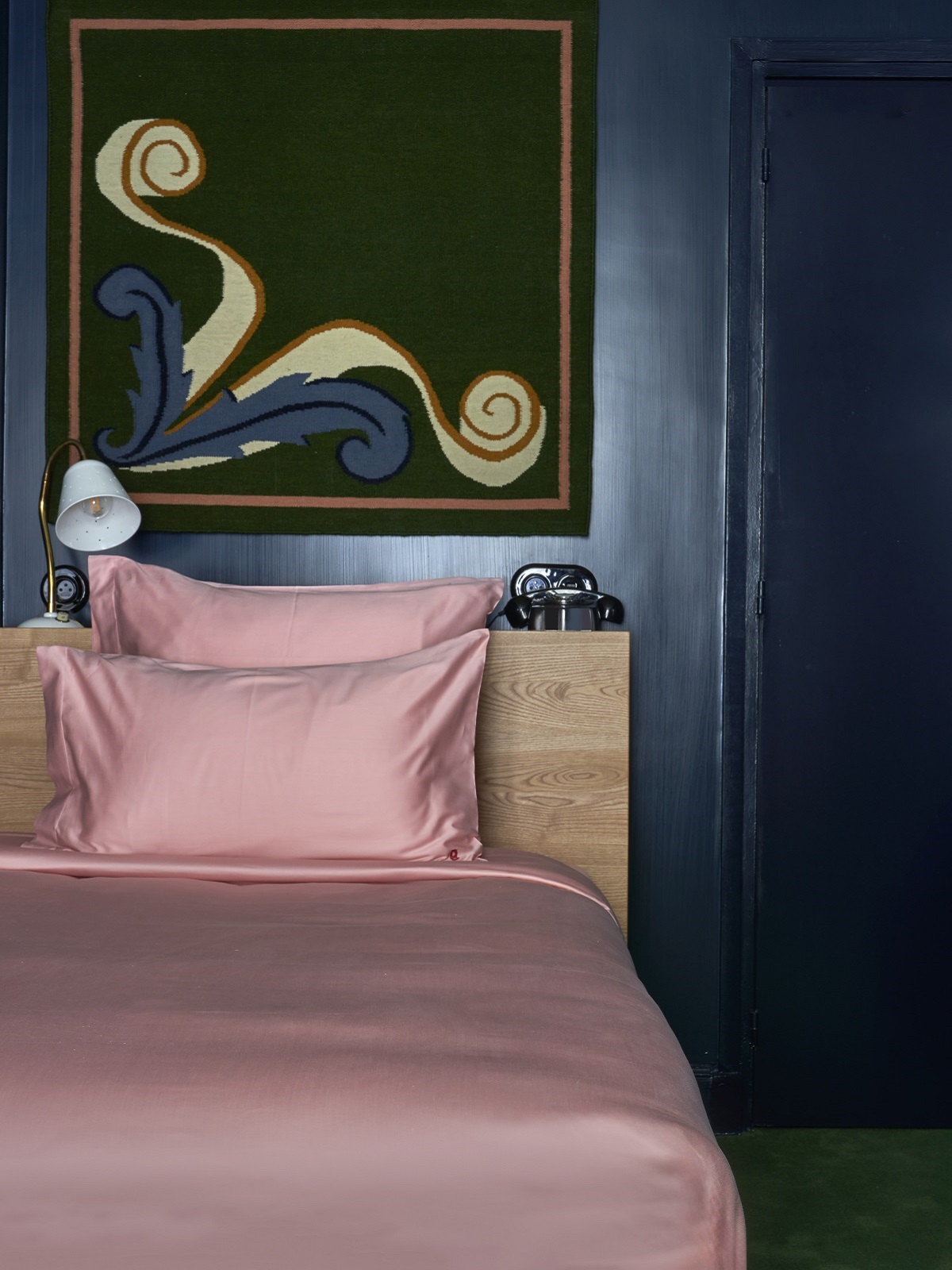 guestroom detail of pink bed linen, blue wall and patterned headboard