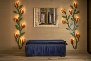 bench seating flanked by statement floral wall lights and a reflective artwork in the middle