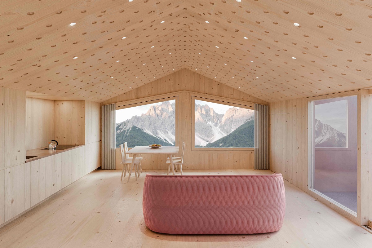 dusty pink couch and wooden table and chairs in stark minimalist interior with mountain view