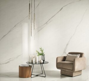 grey and white polished marble effect tile from Atlas concorde on wall behind soft chair and small round table