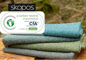 a pile of folded Skopos fabrics under a banner title for carbon neutral organisation