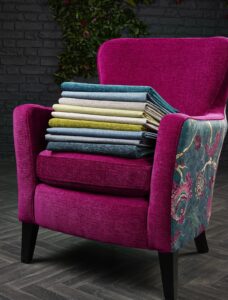 dark purple upholstered chair with contrasting pattern fabric on side panel and swatch of fabrics on the seat