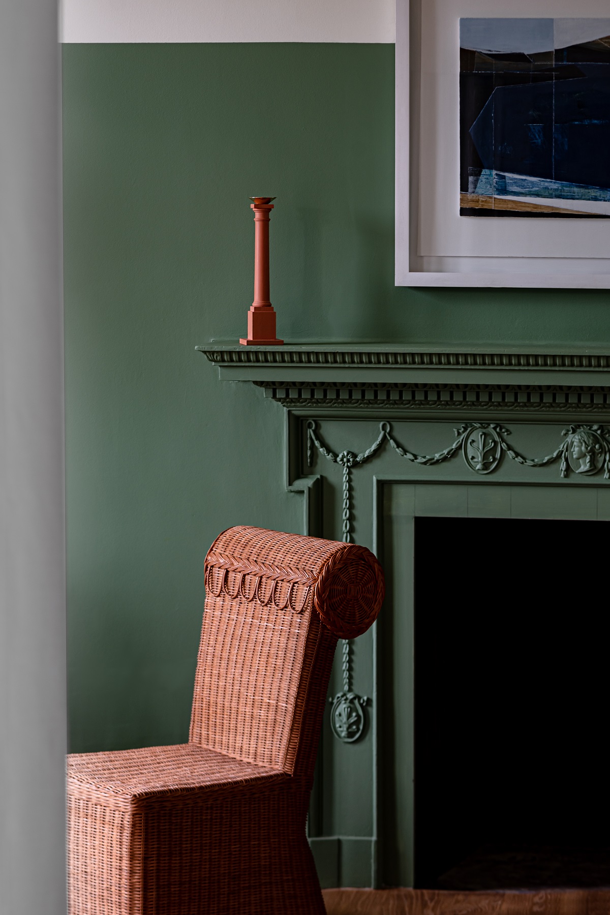 brown wicker chair in front of green period fireplace