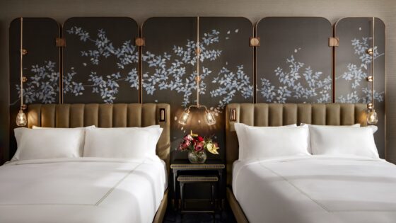 floral Asian inspired wall decoration behind double headboards with ceiling hung focussed lighting in guestroom at Raffles Boston