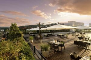lounge and rooftop terrace with tables and chairs under umbrellas with a view across Seoul
