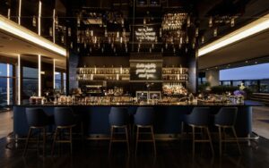 dark central bar with windows on either side and a reflective ceiling in Nyx Bar DoubleTree by Hilton Korea