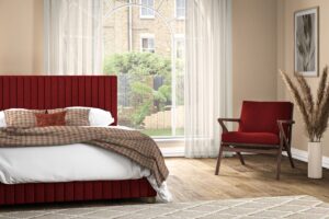 bedroom with bed in front of window with sheer curtains and red chair and headboard
