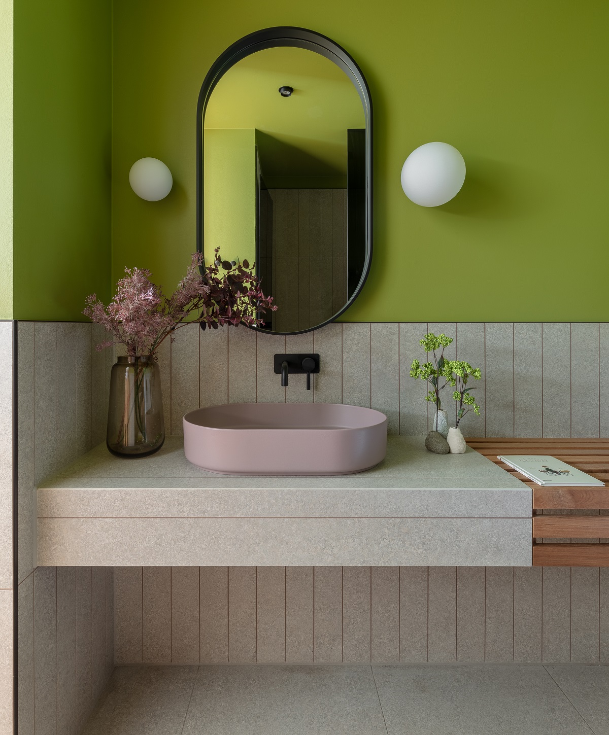 bathroom vanity space with cream tiles and a green wall with dusty pink basin