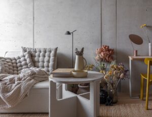 grey and cream couch with cushions next to a small round table with a yellow chair in the corner