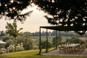 shaded pergola with dining table looking out over Italian countryside