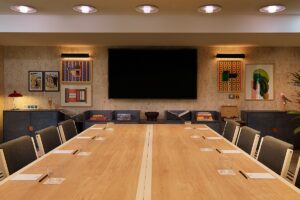 wide wooden meeting table in room with art on the wall behind
