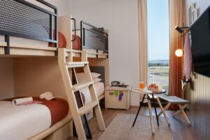 four bunkbeds in light coloured wood frames and metal industrial details with vertical floor to ceiling window