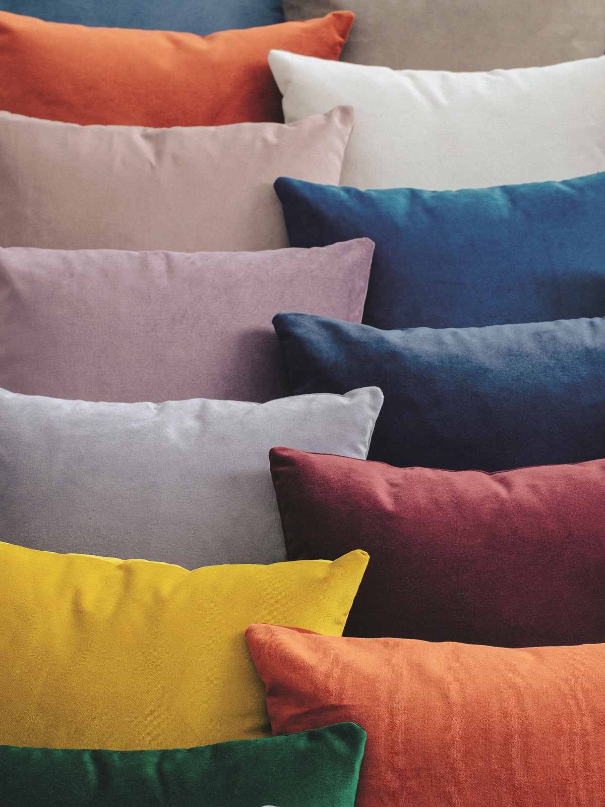 a pile of multicoloured cushions covered in Palazzo velvet from Sekers