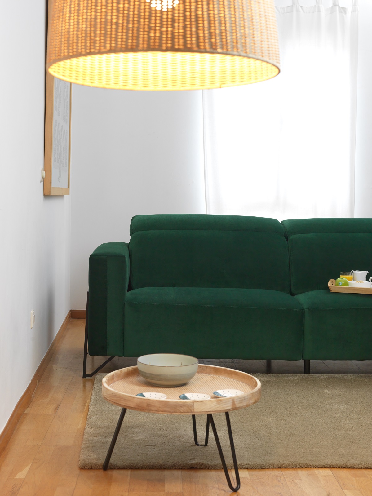 green velvet sofa with wicker lampshade and small wooden table