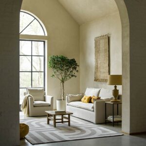 stone coloured chair and sofa with cotton cover in front of arched window on a stone floor